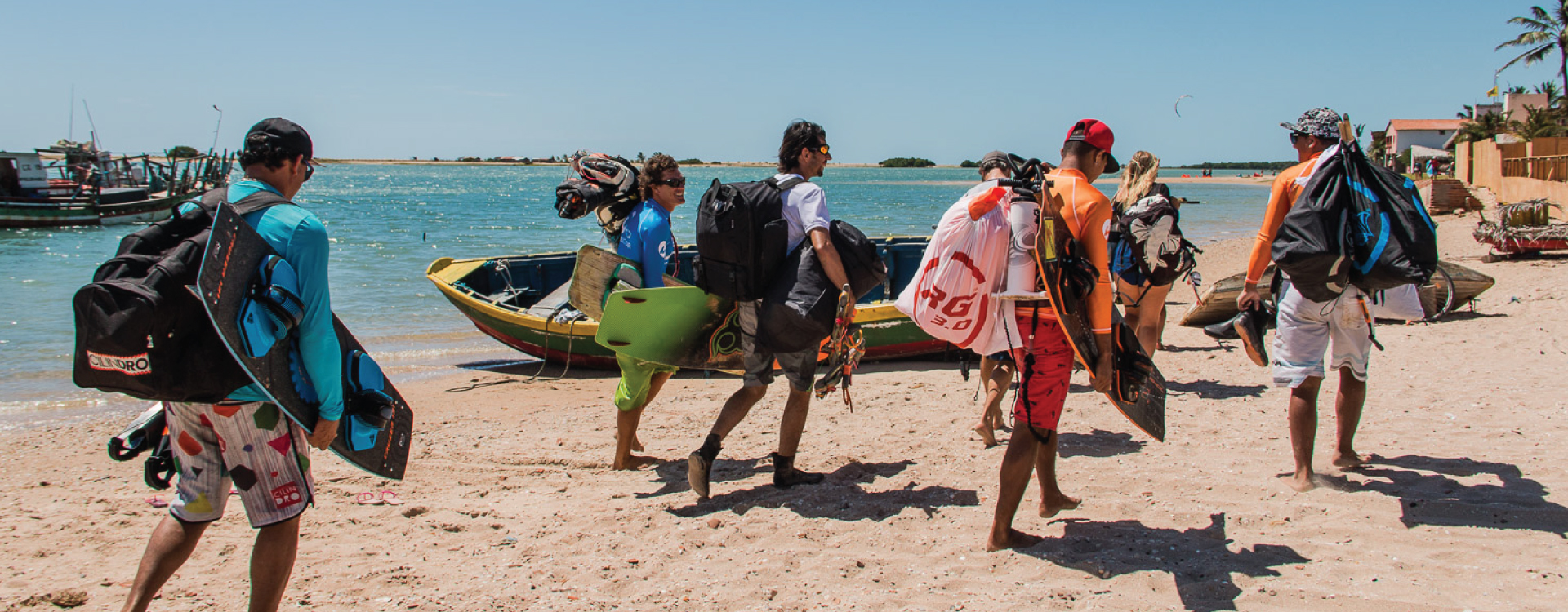 praticantes de kitesurf caminhando na praia